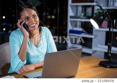 Businesswoman talking on mobile phone in office Businesswoman talking on mobile phone in office 32106056
