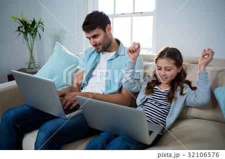 Father and daughter using laptop in the living room 32106576