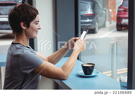 Businesswoman using mobile phone while having coffee Businesswoman using mobile phone while having coffee 32106889