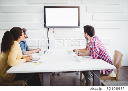 Partners looking at television in creative office 32106985