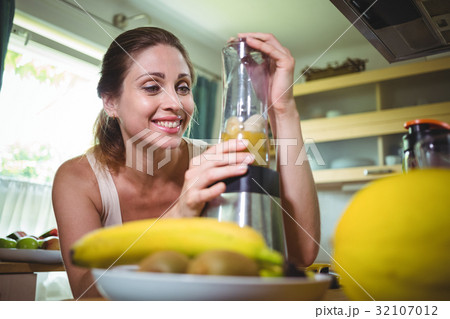 Smiling woman preparing smoothie 32107012
