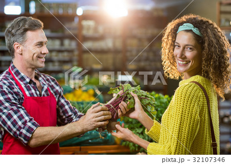 Smiling male staff assisting a woman with grocery shopping Smiling male staff assisting a woman with grocery shopping 32107346