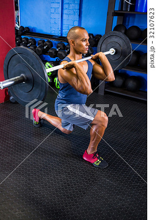 Determined man lifting barbell in fitness studio 32107623