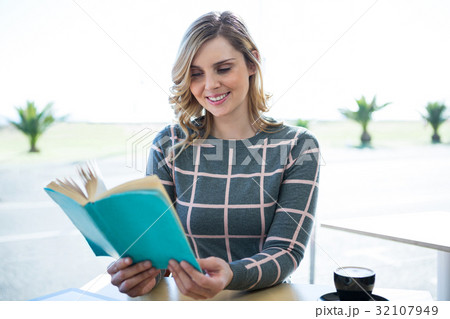 Woman reading novel in cafeteria 32107949
