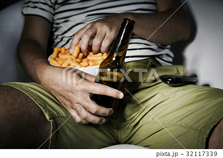man drinking beer and eating cheese puffs 32117339
