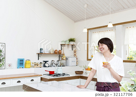 キッチンでグラスを傾ける女性 32117706