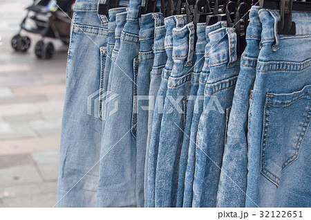 closeup of blue jeans on hangers at the market 32122651