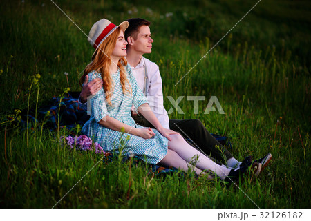 young couple sitting on the plaid in the park young couple sitting on the plaid in the park 32126182