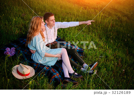 young couple sitting on the plaid in the park  32126189