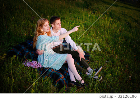 young couple sitting on the plaid in the park a 32126190