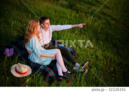 young couple sitting on the plaid in the park young couple sitting on the plaid in the park 32126191