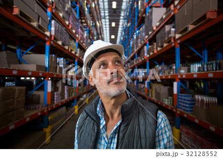 Warehouse worker looking at cardboard boxes on shelves Warehouse worker looking at cardboard boxes on shelves 32128552