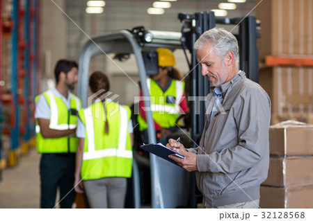Warehouse manager writing on clipboard 32128568