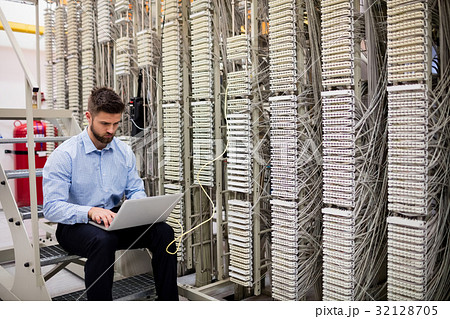 Technician using laptop while analyzing server Technician using laptop while analyzing server 32128705