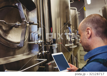 Male manufacturer using digital tablet by machinery Male manufacturer using digital tablet by machinery 32128717