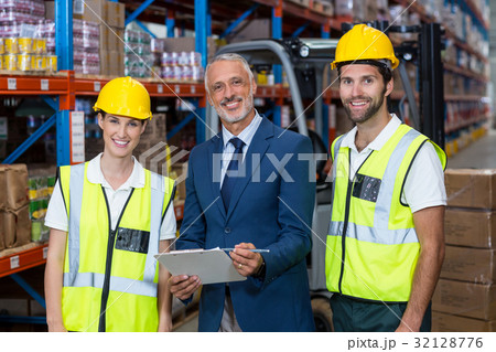 Portrait of wrehouse manager and co-workers standing with clipboard 32128776