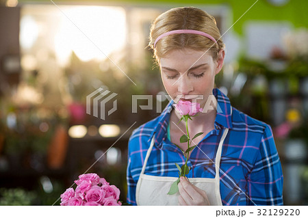 Female florist smelling pink rose Female florist smelling pink rose 32129220
