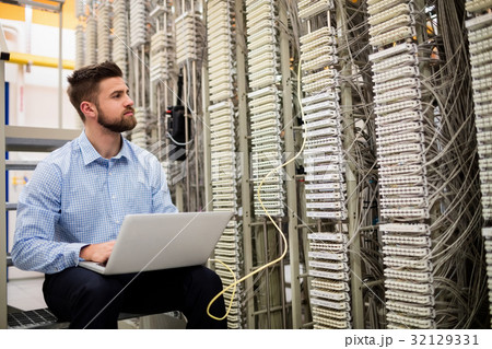 Technician using laptop while analyzing server Technician using laptop while analyzing server 32129331