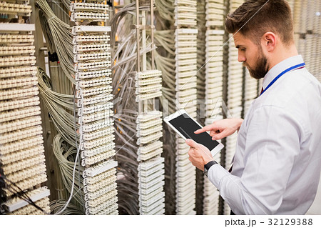 Technician using digital tablet while analyzing server Technician using digital tablet while analyzing server 32129388