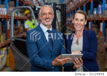 Warehouse manager and client discussing over digital tablet 32129848