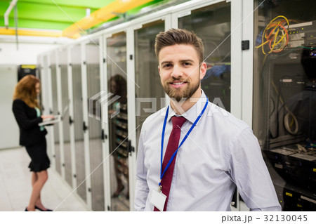 Smiling technician standing in a server room Smiling technician standing in a server room 32130045
