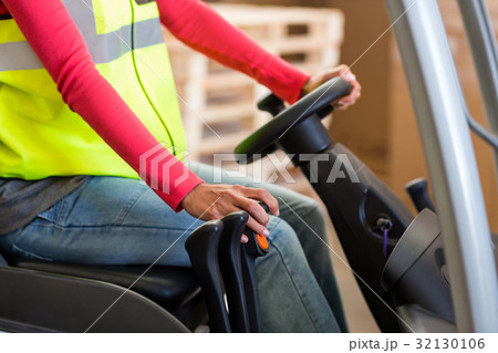 Mid section of warehouse worker using a forklift 32130106