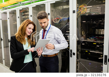 Technicians using digital tablet while analyzing server Technicians using digital tablet while analyzing server 32130276