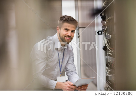 Technician using digital tablet while analyzing server 32130286