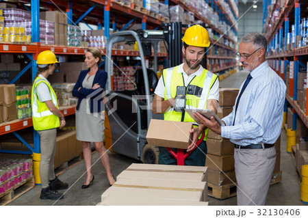 Warehouse manager holding digital tablet while male worker scanning barcode Warehouse manager holding digital tablet while male worker scanning barcode 32130406