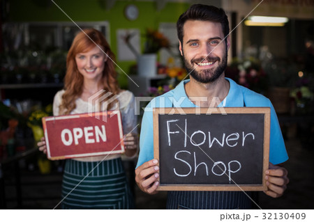Man holding slate with flower shop sign and woman holding open signboard Man holding slate with flower shop sign and woman holding open signboard 32130409