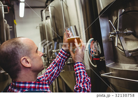 Brewery worker inspecting beer in glass Brewery worker inspecting beer in glass 32130758