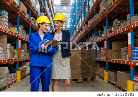 Warehouse manager and worker discussing with clipboard 32130882