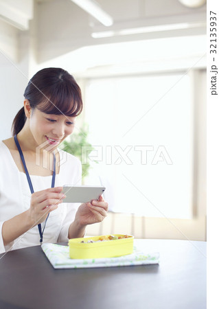 スマホでお弁当の写真を撮る女性 ランチ お弁当の写真素材