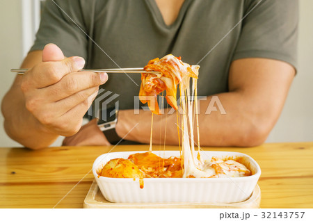 Man eating cheese Tokboki in a canteen. 32143757