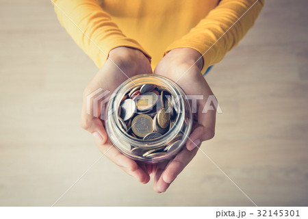 Woman hands holding glass jar with coins inside 32145301