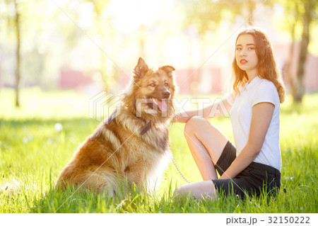 Teenage smiling girl with her dog sitting in park Teenage smiling girl with her dog sitting in park 32150222