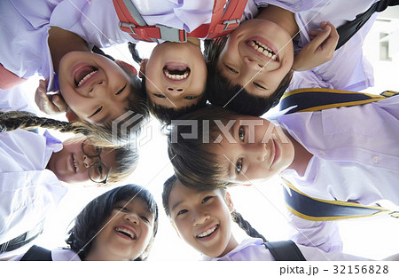 Shoolchildren are gathering and smiling . 32156828