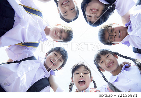 Schoolchildren in uniforms are smiling and gathering in a round 32156831