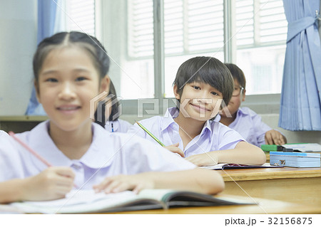 students are sitting, holding a pen and smiling in classroom. 32156875