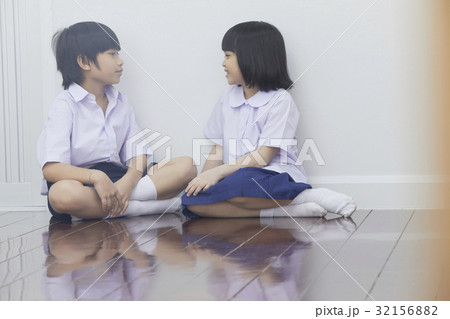 two pupils are sitting on floor and chatting together two pupils are sitting on floor and chatting together 32156882