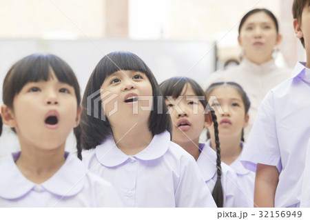 Students are singing national anthem and looking at something seriously 32156949