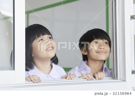 two children are looking at something from the window 32156964