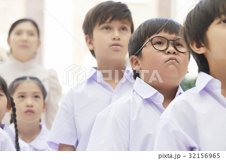 students and teacher are standing and looking at something 32156965
