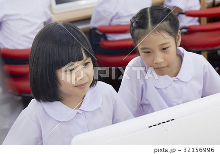 Two schoolgirls are looking at computer and studying. 32156996