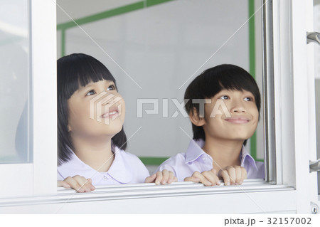 Children are smiling and looking at something outside the class. 32157002
