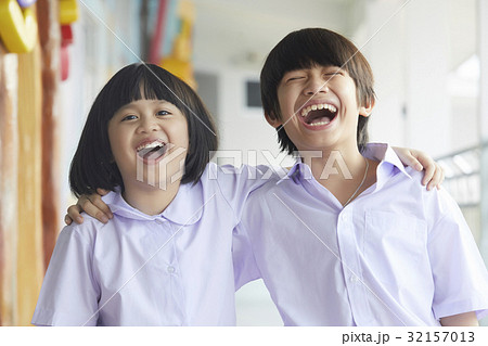 A portrait of two children laughing and putting arms on shoulders. 32157013