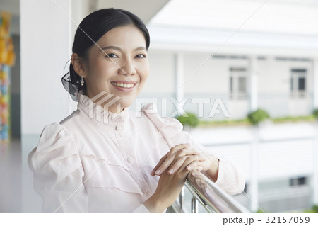 The teacher is standing and smiling near the balcony 32157059