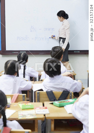 a photo of a teacher standing and writing on a board for pupils. a photo of a teacher standing and writing on a board for pupils. 32157104