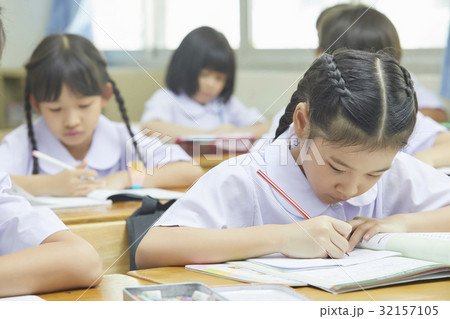 a photo of schoolchildren sitting and writing in a class. 32157105