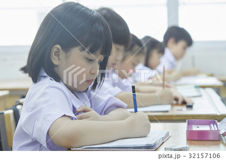 a photo of pupils focusing on writing something in classroom. 32157106